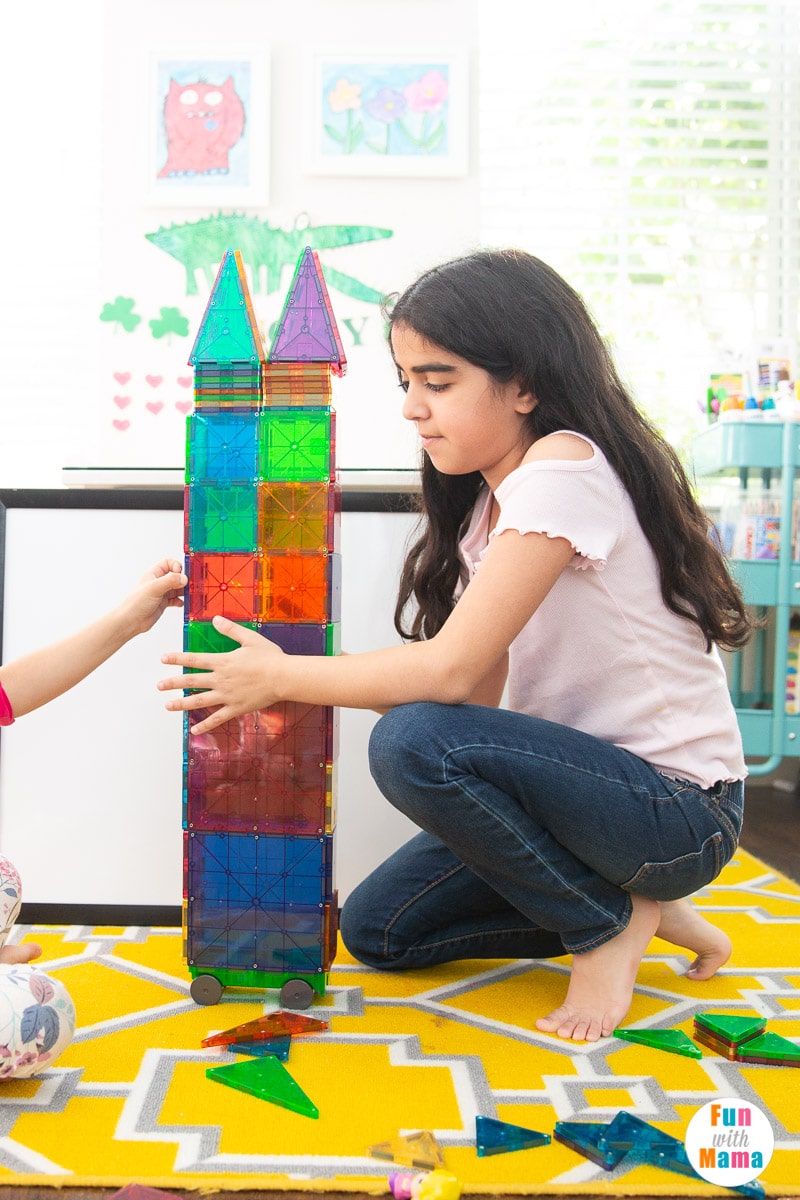 older child building a large tower with magnetic tiles 