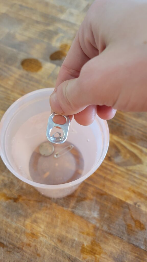 adding a soda tab to a cup of water 