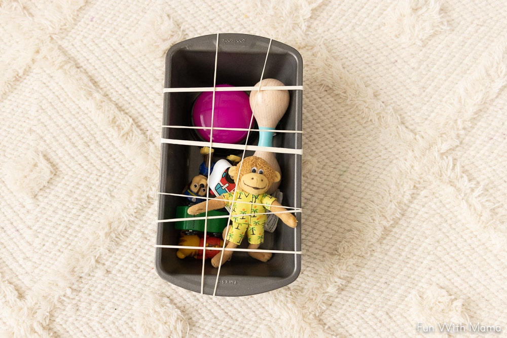baking pan with rubber bands and toys inside 
