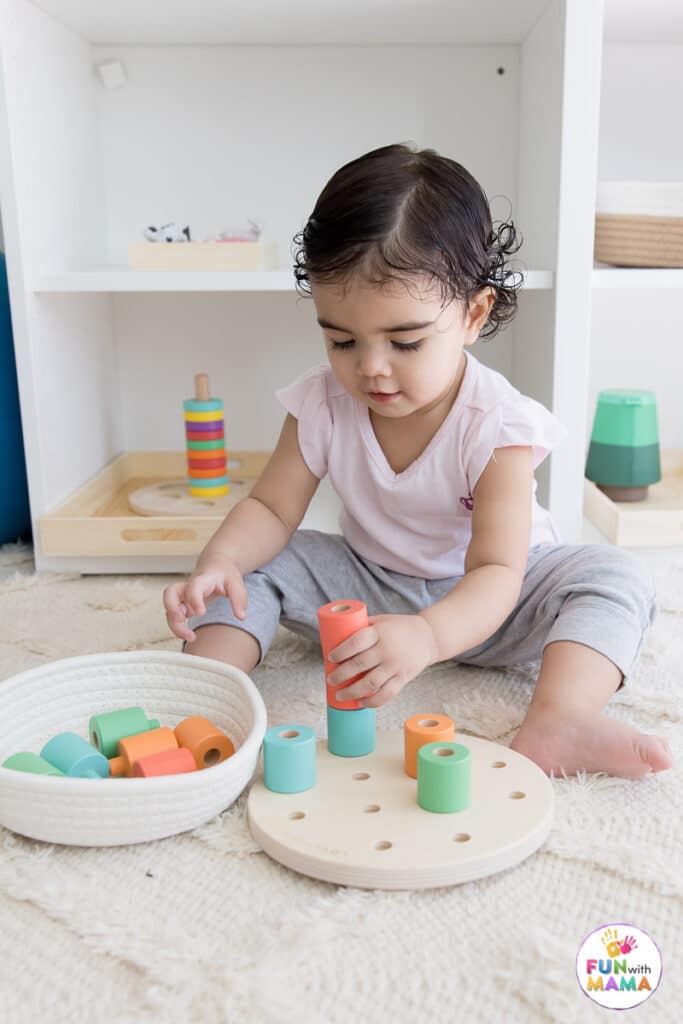 baby playing with a wooden peg board 