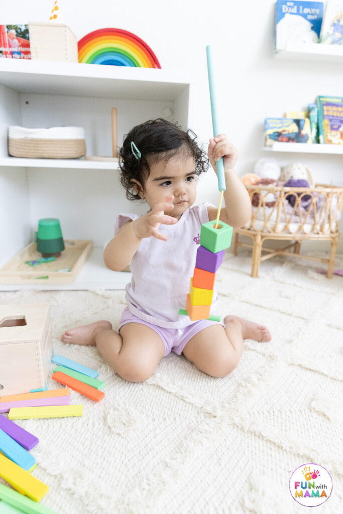 toddler playing with rope and wooden beads 